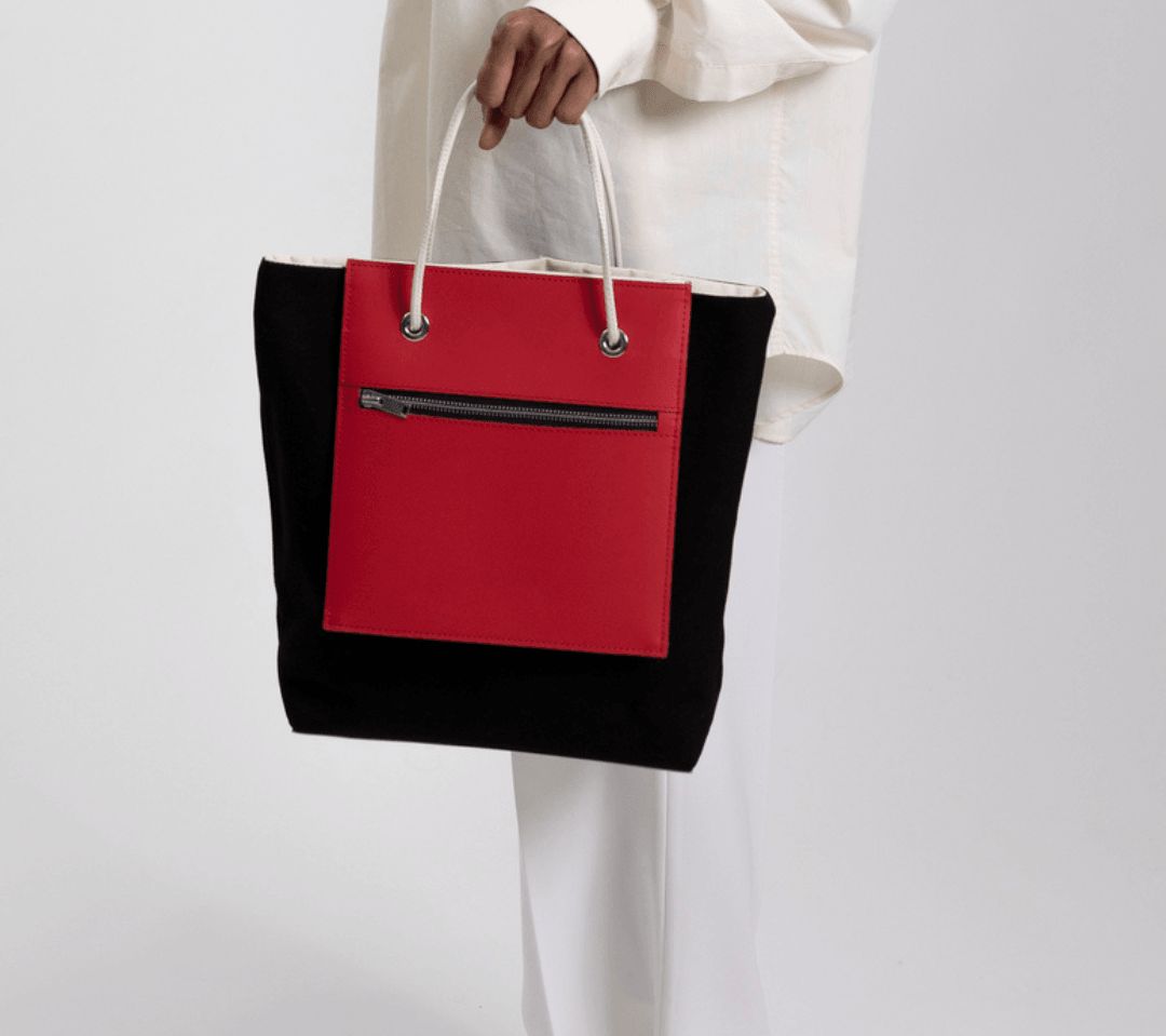 Un Sac à main noir et rouge de fourre-tout réversible et de moyenne capacité