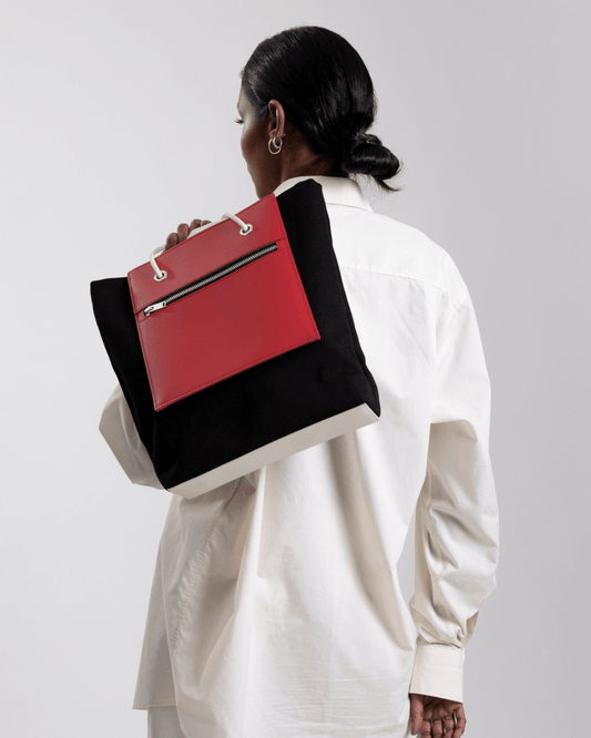Un Sac à main noir et rouge de fourre-tout réversible et de moyenne capacité
