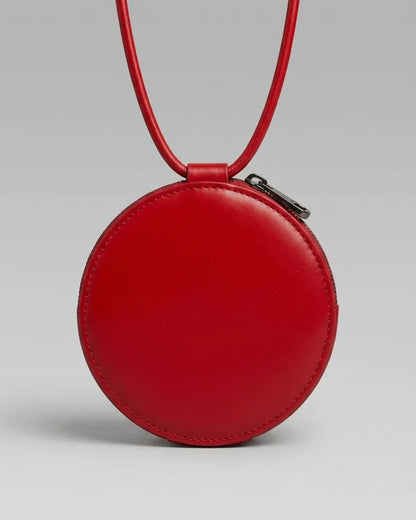 Mini sac rond en cuir rouge Almita Mini porté avec sa bandoulière
