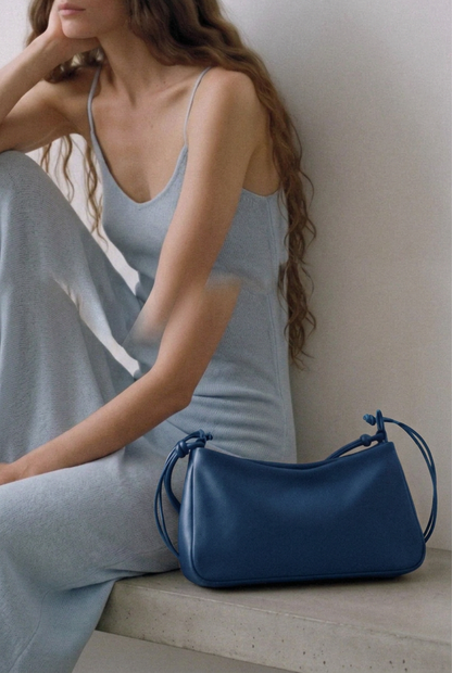 Sac MariLoli en cuir bleu posé sur un banc à côté d’une femme assise