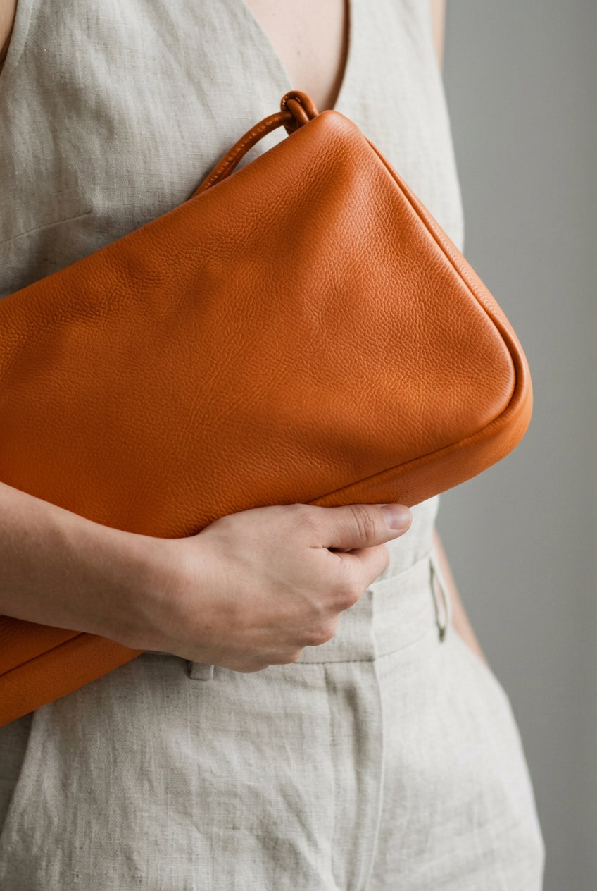 Gros plan du sac MariLoli en cuir orange tenu contre soi