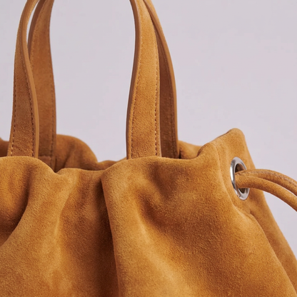 Petit sac à main Angelines en cuir à l’aspect suédé jaune moutarde en gros plan montrant la texture mate et veloutée, Bmassy.