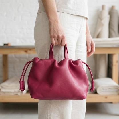 Petit sac à main Angelines en cuir rose framboise tenu à la main par ses poignées, Bmassy.
