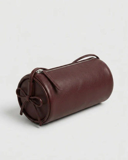 Sac Alma bordeaux de forme cylindrique, vu de trois quarts avec fermeture zippée et cordon noué sur le côté