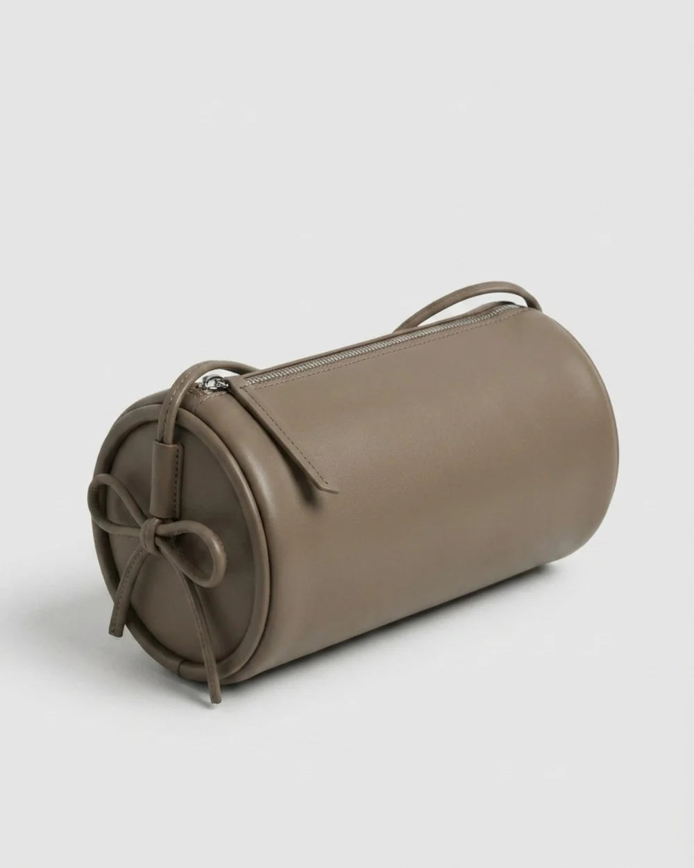 Sac Alma en cuir gris de forme cylindrique, vu de trois quarts sur fond clair, avec cordon noué sur le côté et fermeture zippée