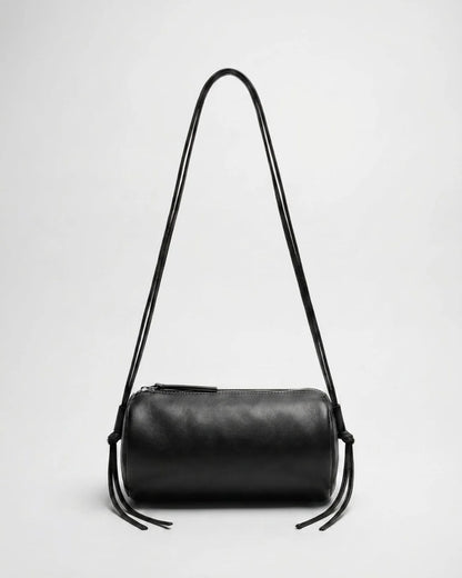 Sac Alma en cuir noir de forme cylindrique, présenté avec ses longs cordons relevés en bandoulière