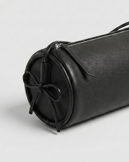 Gros plan du sac Alma en cuir noir, montrant le côté rond, le cordon noué et la fermeture zippée