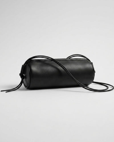 Sac Alma en cuir noir de forme cylindrique avec ses longs cordons déployés
