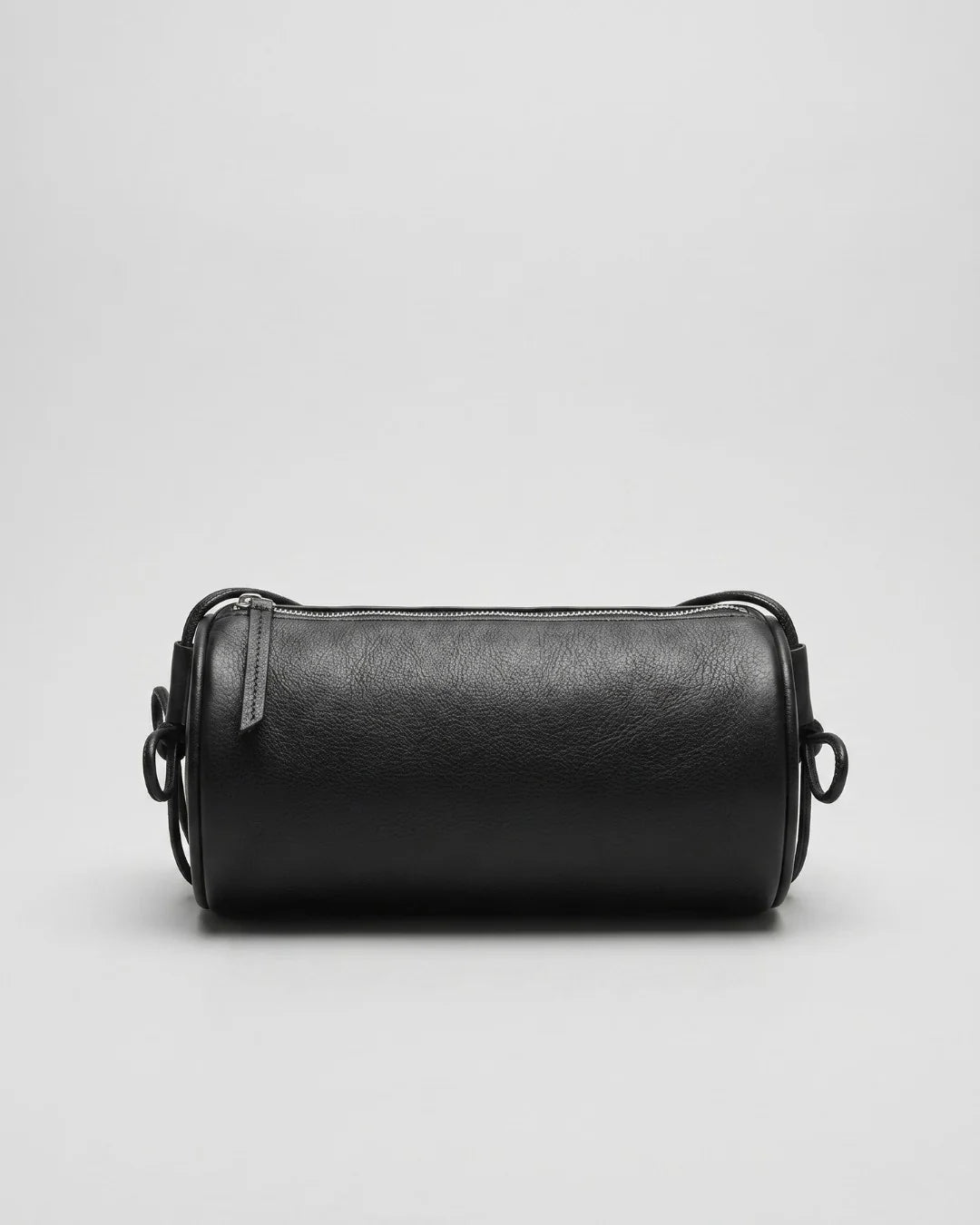 Sac Alma en cuir noir vu de face avec fermeture zippée et cordons noués sur les côtés