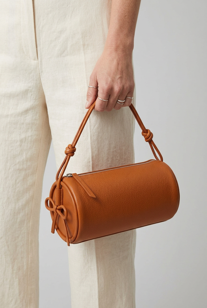 Sac Alma orange porté à la main par ses cordons noués