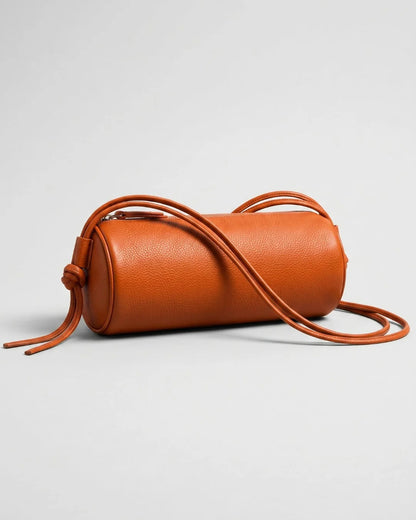 Sac Alma orange de forme cylindrique, posé avec ses longs cordons déployés devant