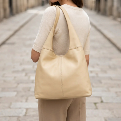 Sac à main beige porté à l’épaule par une femme vue de dos