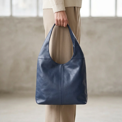Sac à main bleu tenu par sa large anse, le long de la jambe