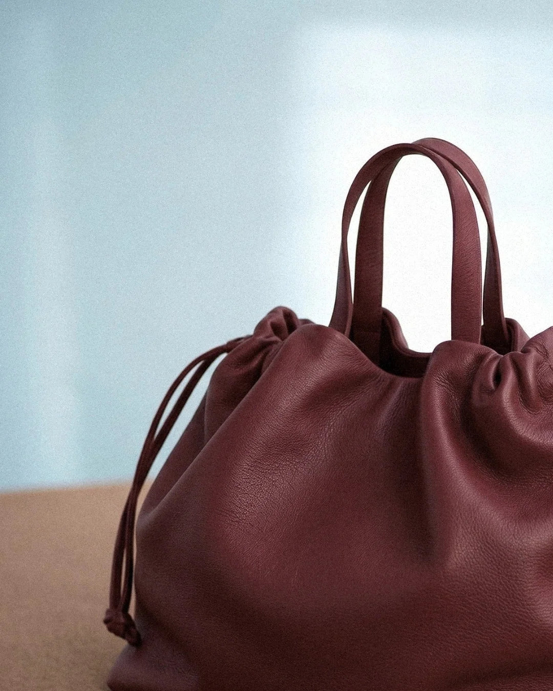 Sac à main Angela Medium en cuir bordeaux en vue rapprochée montrant la texture du cuir et les poignées, Bmassy.