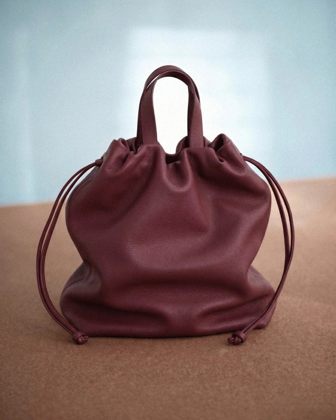 Sac à main Angela Medium en cuir bordeaux vu de face avec ses poignées et ses cordons de serrage, Bmassy.