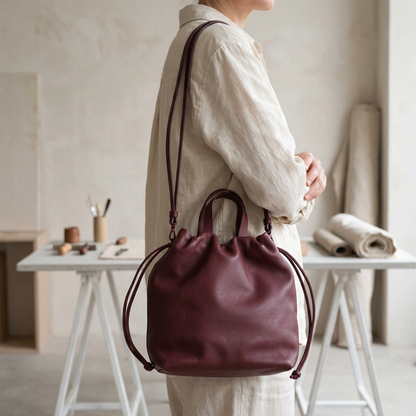 Sac à main Angela Medium en cuir bordeaux porté à l’épaule avec sa bandoulière, Bmassy.
