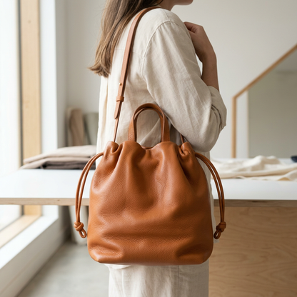 Sac à main Angela Medium en cuir orange cuivré porté à l’épaule avec sa bandoulière, Bmassy.