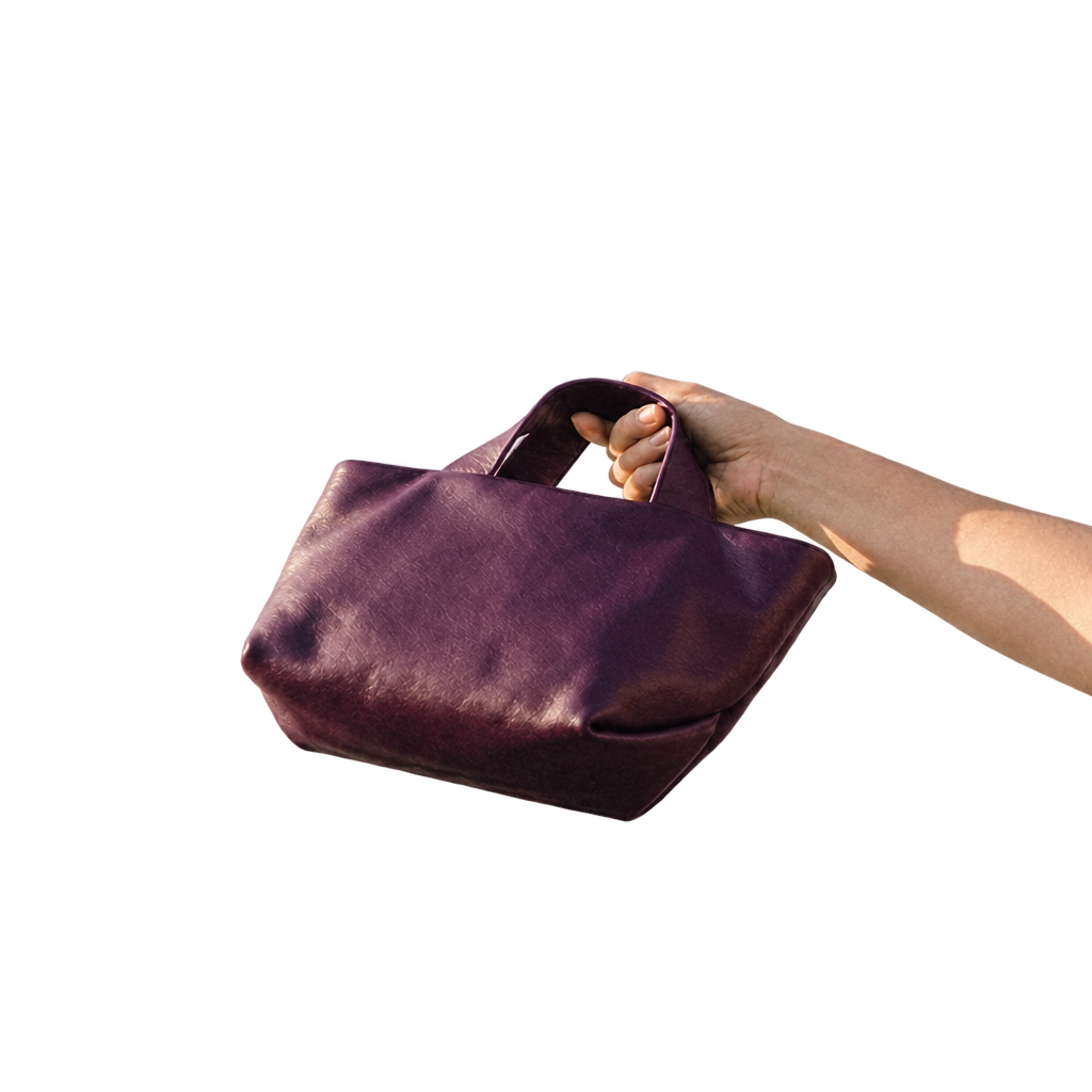 Sac Juanita en cuir aubergine clair, tenu à la main et incliné pour montrer son fond, Bmassy.