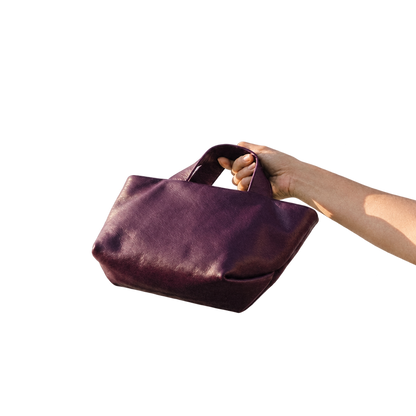 Sac Juanita en cuir aubergine clair, tenu à la main et incliné pour montrer son fond, Bmassy.