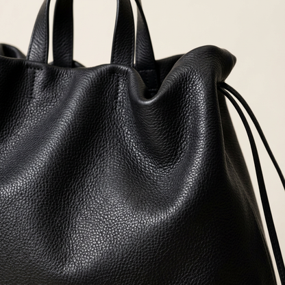 Gros plan sur le grain et les plis du cuir noir du sac Dona Angela, Bmassy.