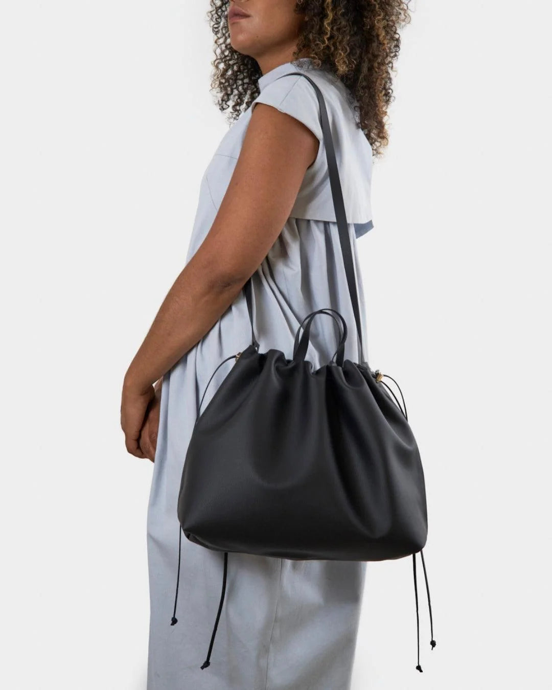 Sac à main maxi Dona Angela en cuir noir porté à l’épaule avec sa bandoulière, en vue rapprochée, Bmassy.