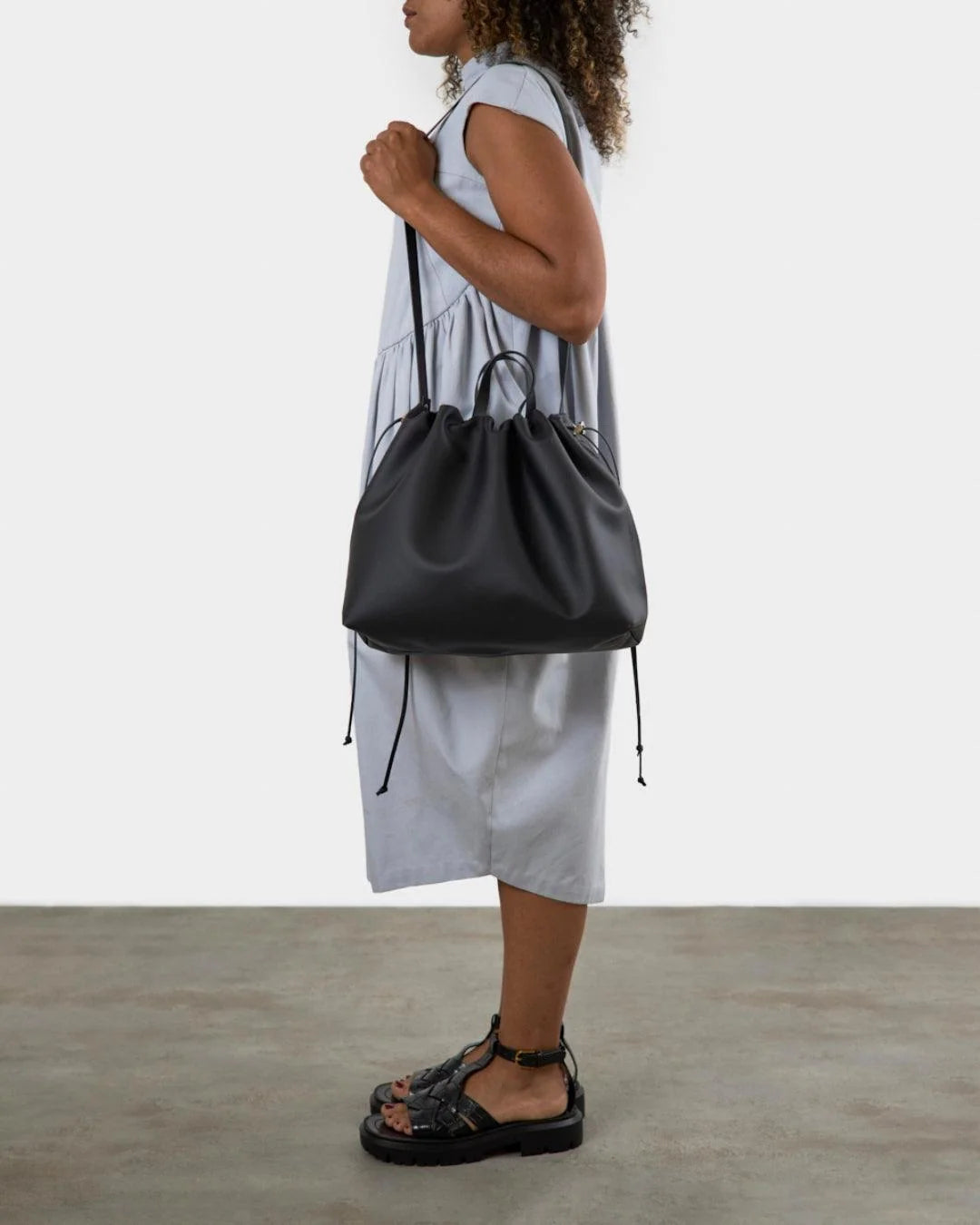 Sac à main maxi Dona Angela en cuir noir porté à l’épaule, avec la silhouette de profil, Bmassy.
