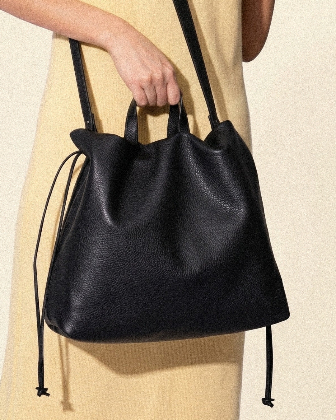 Sac à main maxi Dona Angela en cuir noir tenu à la main par ses poignées, avec sa bandoulière visible, Bmassy.