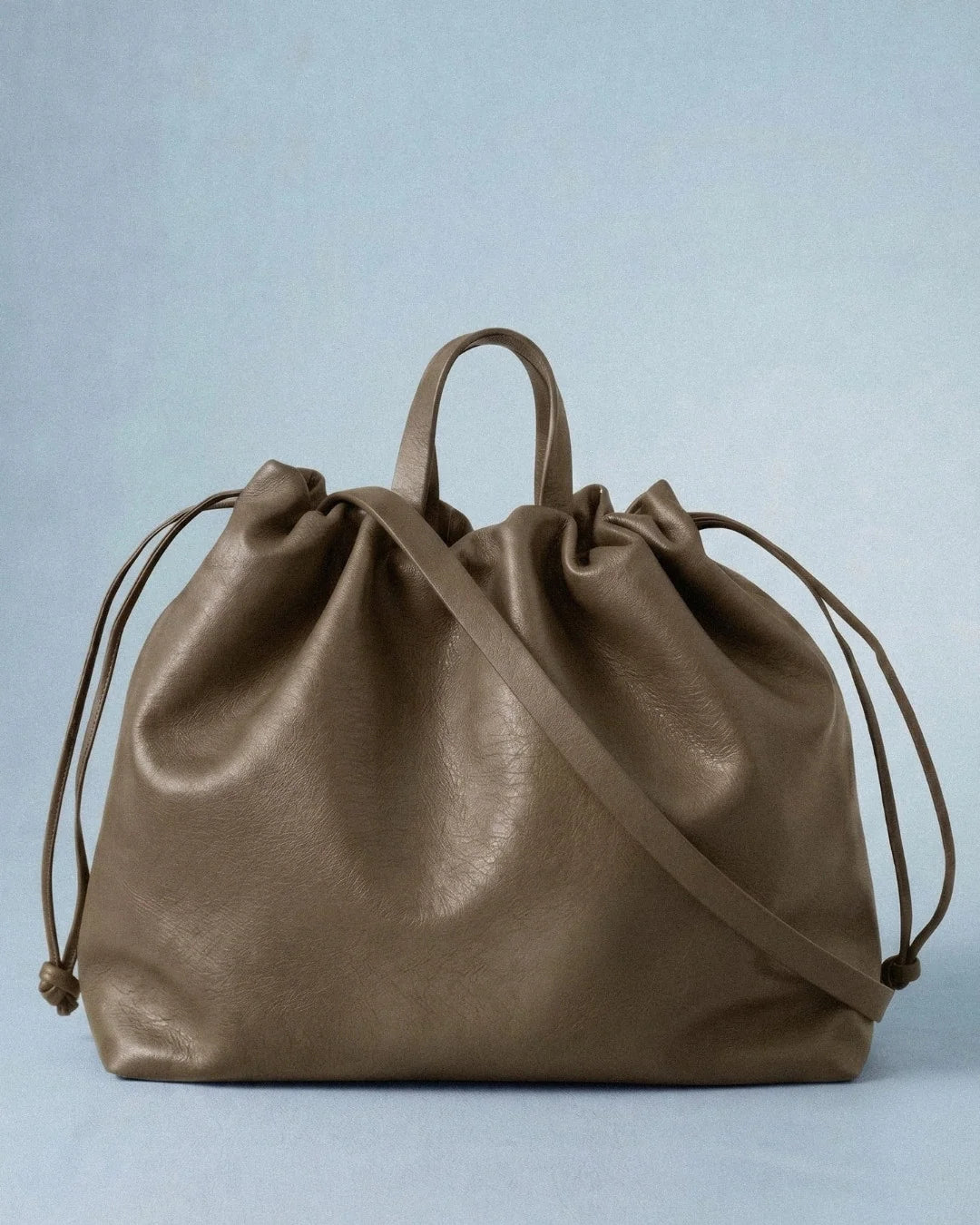 Sac à main maxi Dona Angela en cuir taupe vu de face avec ses poignées, sa bandoulière et ses cordons de serrage, Bmassy.