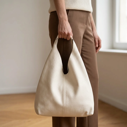 Sac shopper en cuir grainé blanc tenu à la main par son anse, le long de la jambe