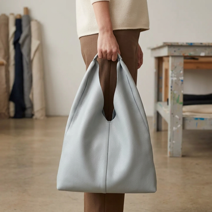 Sac shopper en cuir gris clair tenu à la main par son anse