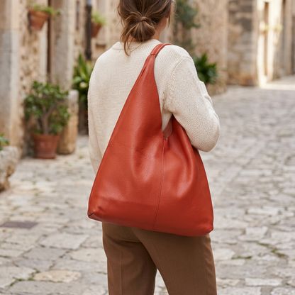 Sac shopper en cuir grainé rouge porté à l’épaule par une femme vue de dos