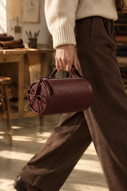 Sac Alma bordeaux tenu à la main par sa poignée courte dans un atelier