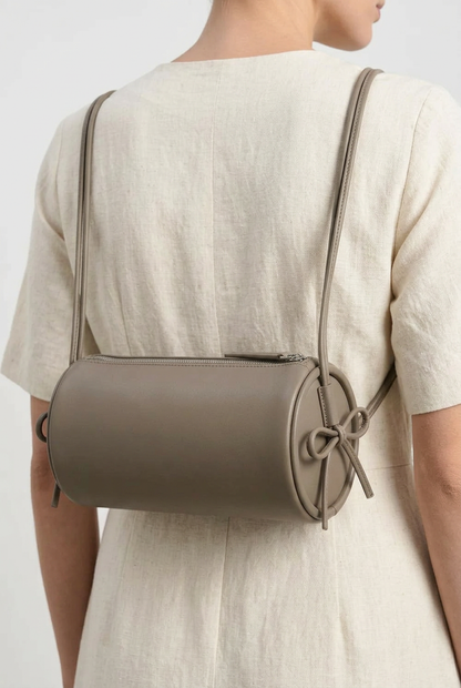 Sac Alma en cuir gris de forme cylindrique, porté en sac à dos avec ses deux cordons sur les épaules