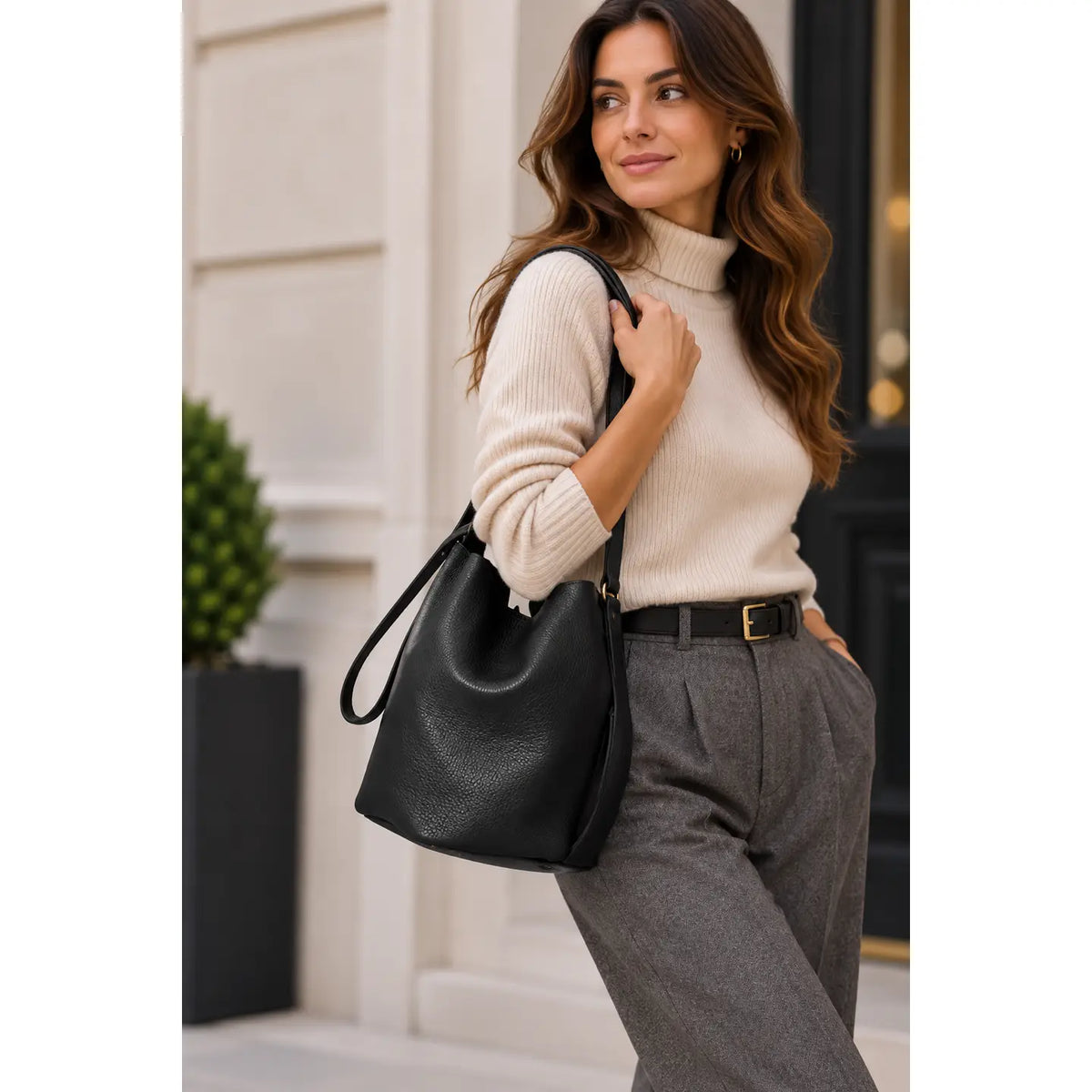 Sac seau noir porté à l’épaule par une femme en haut écru 
