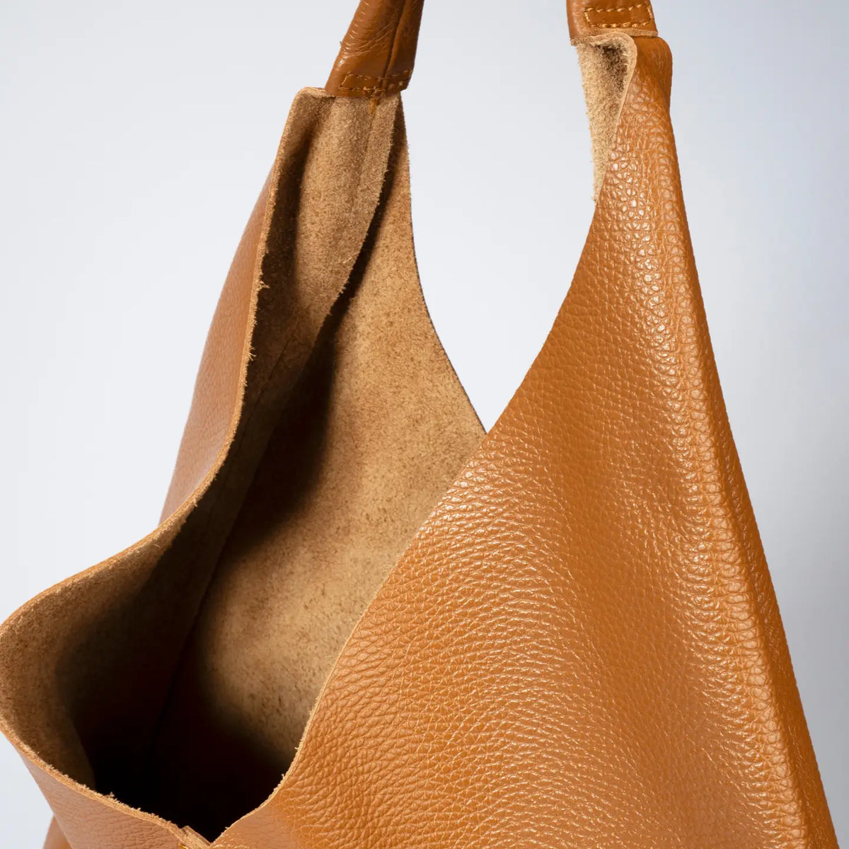 Gros plan sur le cuir grainé camel du sac shopper, montrant son ouverture et l’intérieur de l’anse