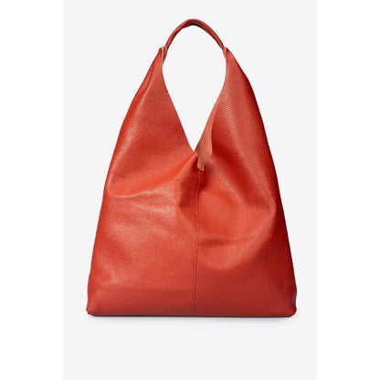 Sac shopper en cuir grainé rouge posé sur un banc en bois clair, vu de face
